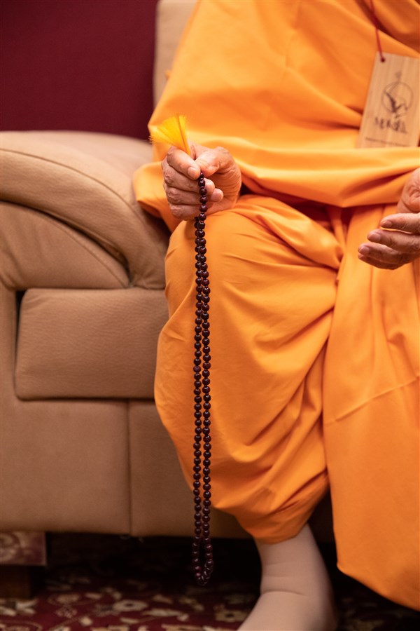 Swamishri performs mala as he listens to the presentations