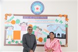 Sh. Lalit Padalia posing before the school display board with campus director, Dr. Neeta Shah