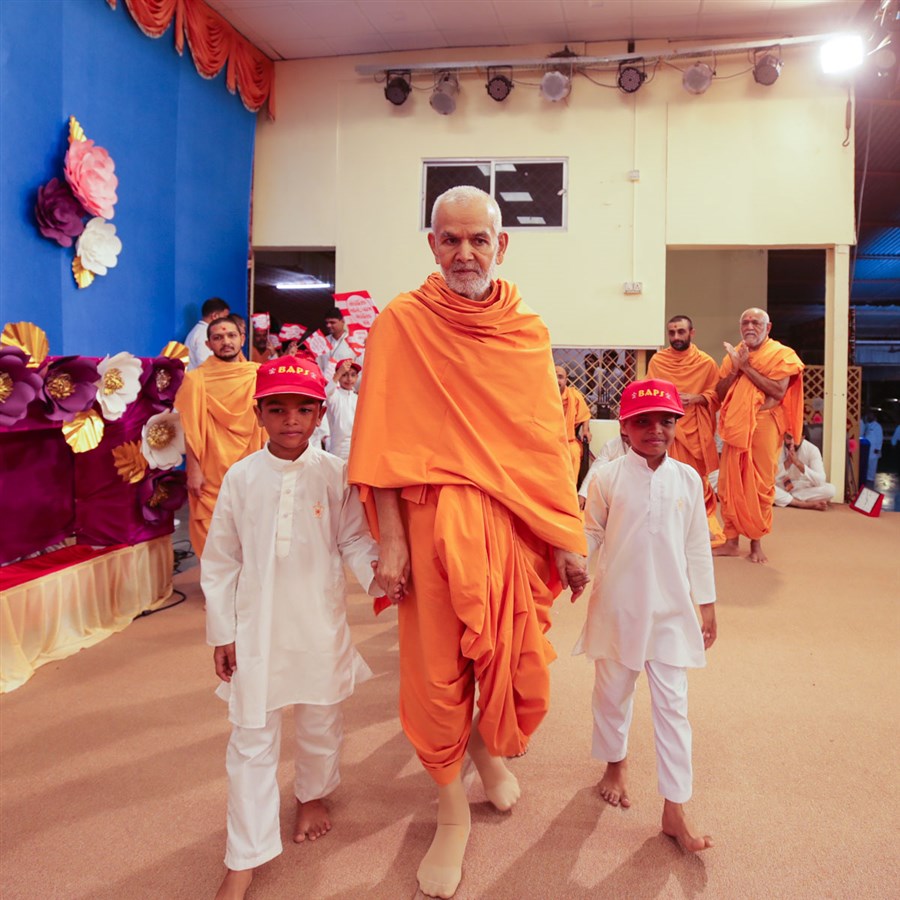 Children accompany Swamishri on to the stage