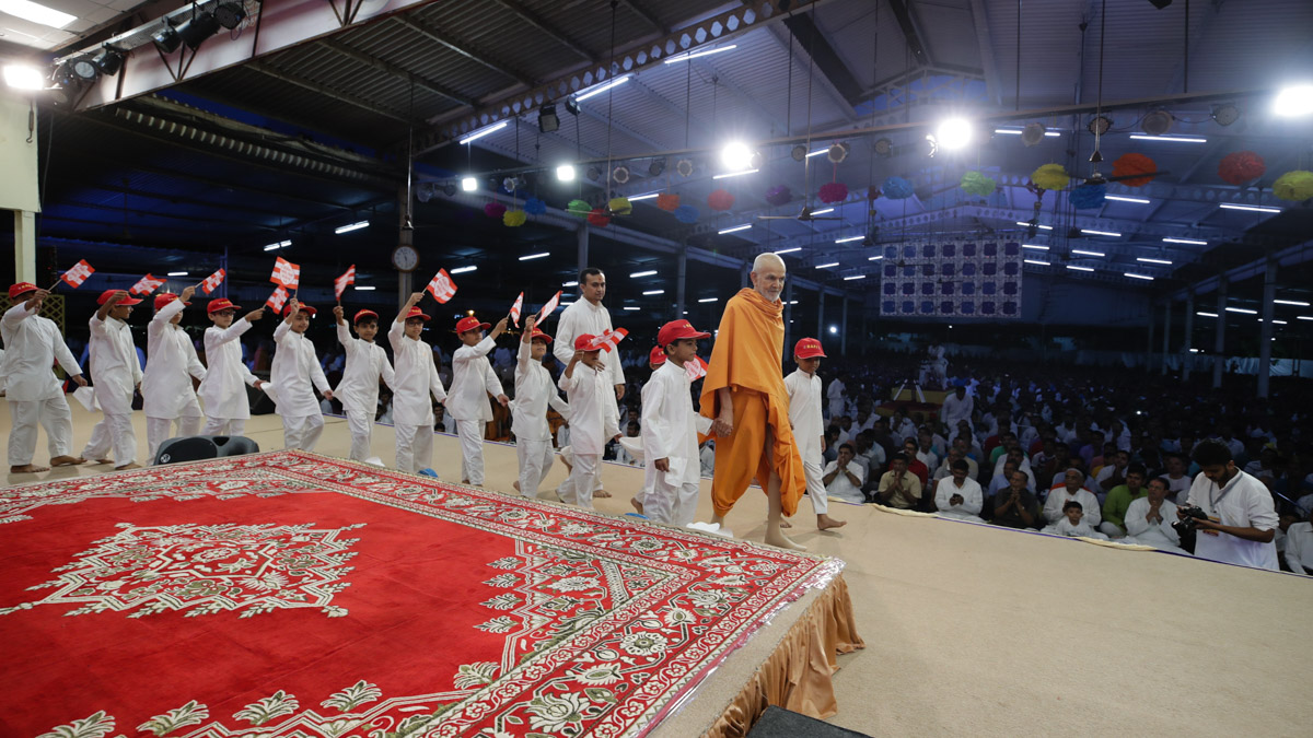 Children accompany Swamishri on to the stage