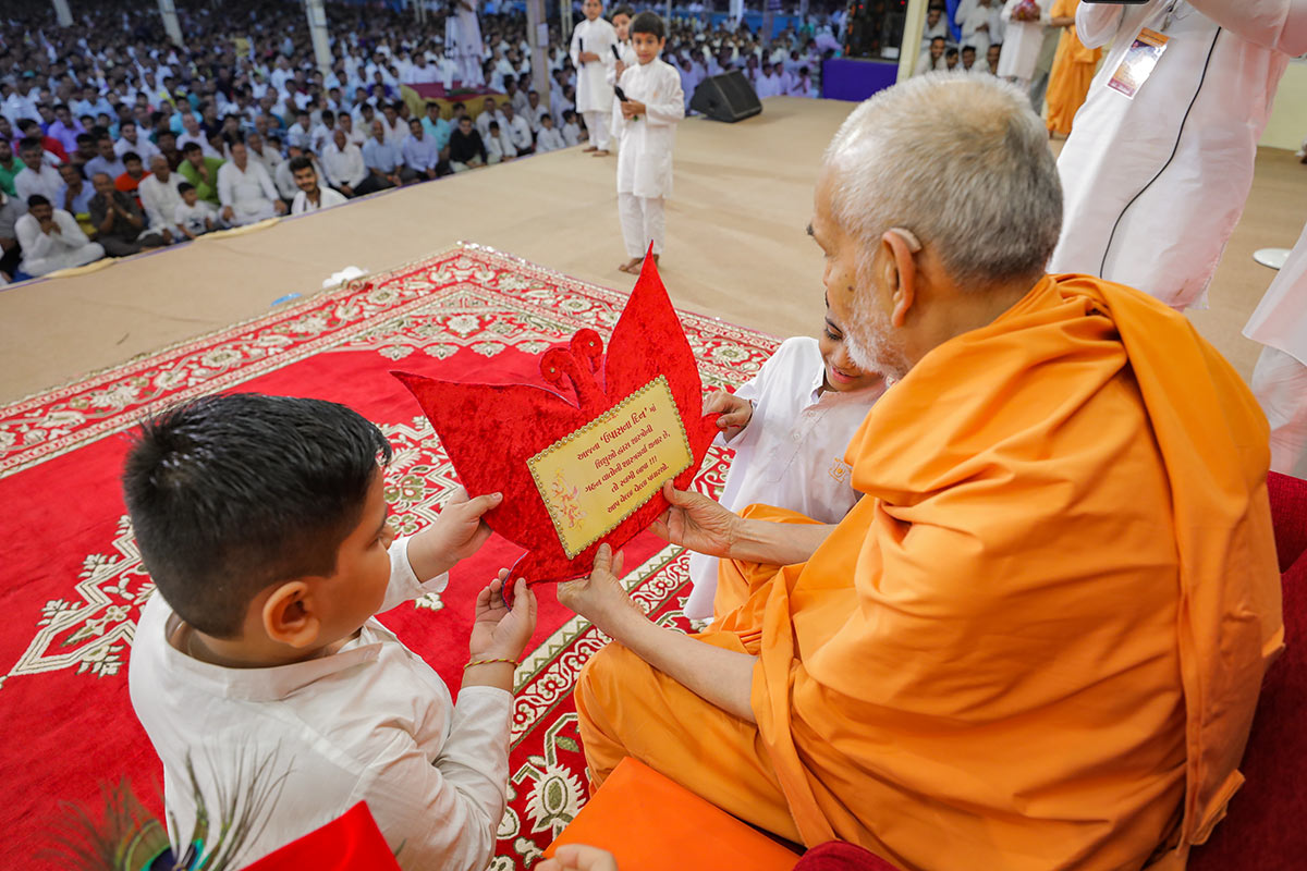 Swamishri observes a card prepared by children