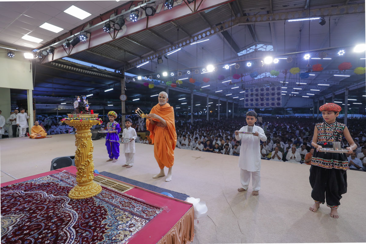 Swamishri and children perform the evening arti