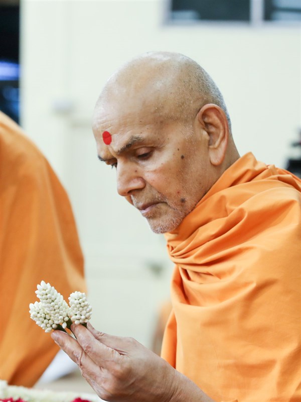 Swamishri observes a flower ornament