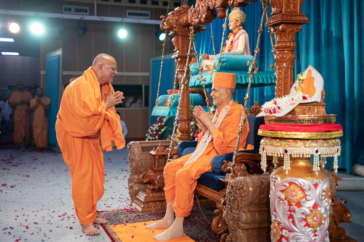Pujya Ishwarcharan Swami welcomes Swamishri with a garland