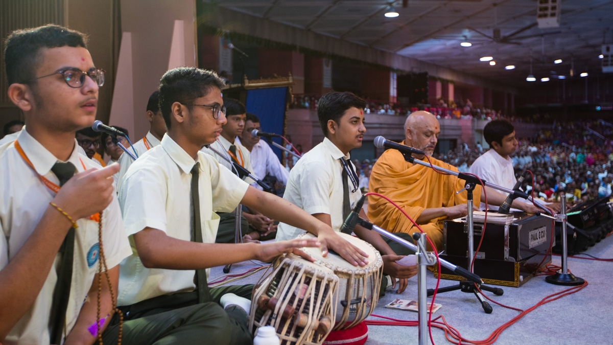 Students of BAPS Swaminarayan Vidyamandir, Raisan, sing kirtans in Swamishri's puja