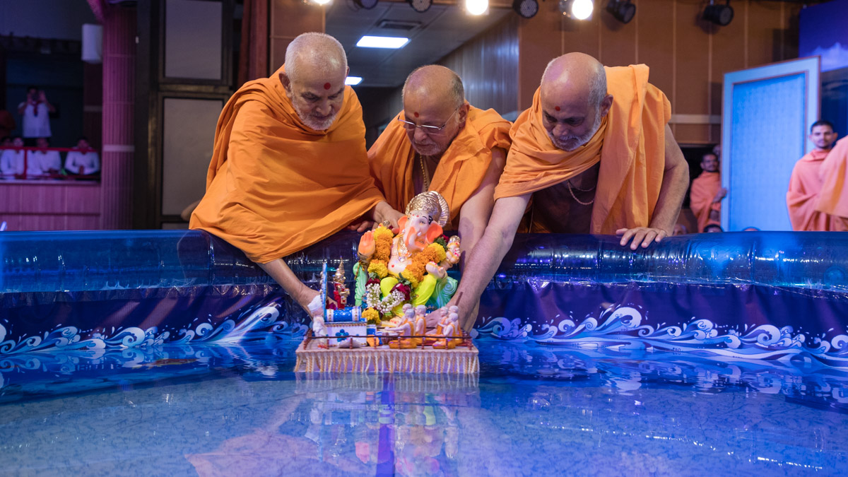 Swamishri, Pujya Ishwarcharan Swami and Pujya Viveksagar Swami immerse Shri Ganapatiji in the water