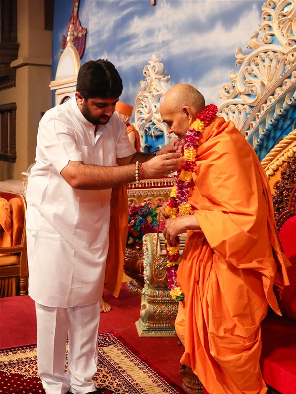 Shri Bhailu Bapu honors Swamishri with a garland