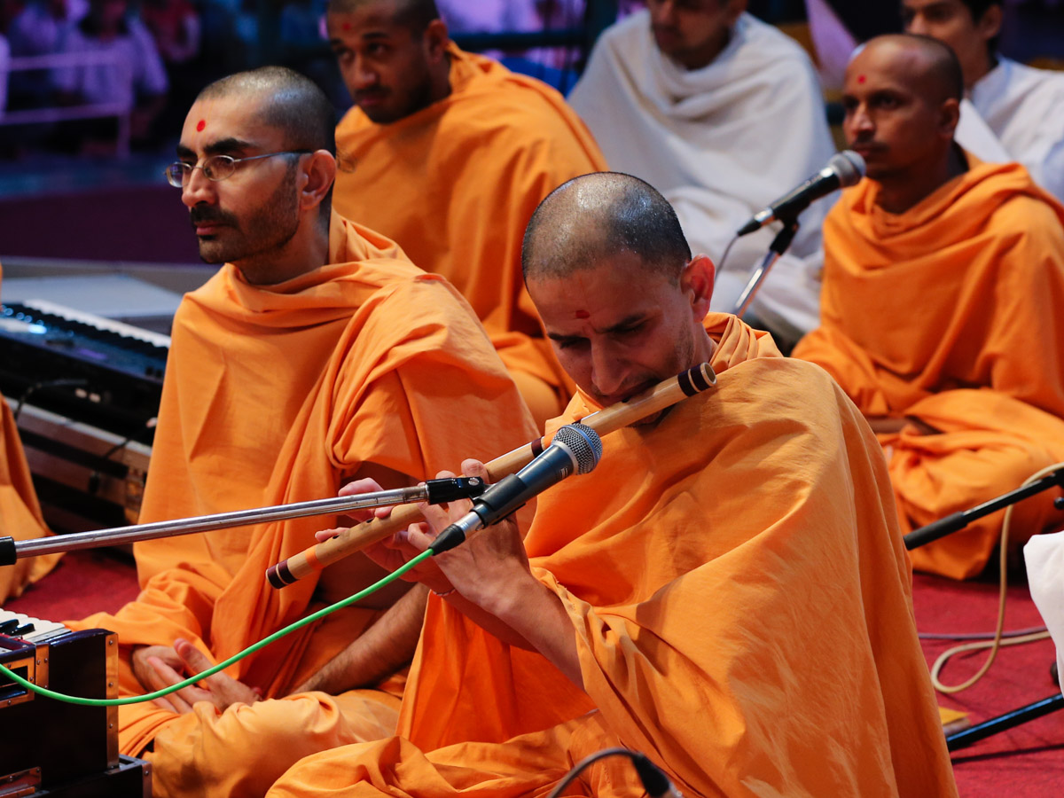 Dharmaseva Swami plays the flute in Swamishri's morning puja