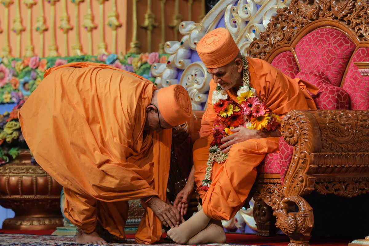 Pujya Kothari Swami honors Swamishri with a garland