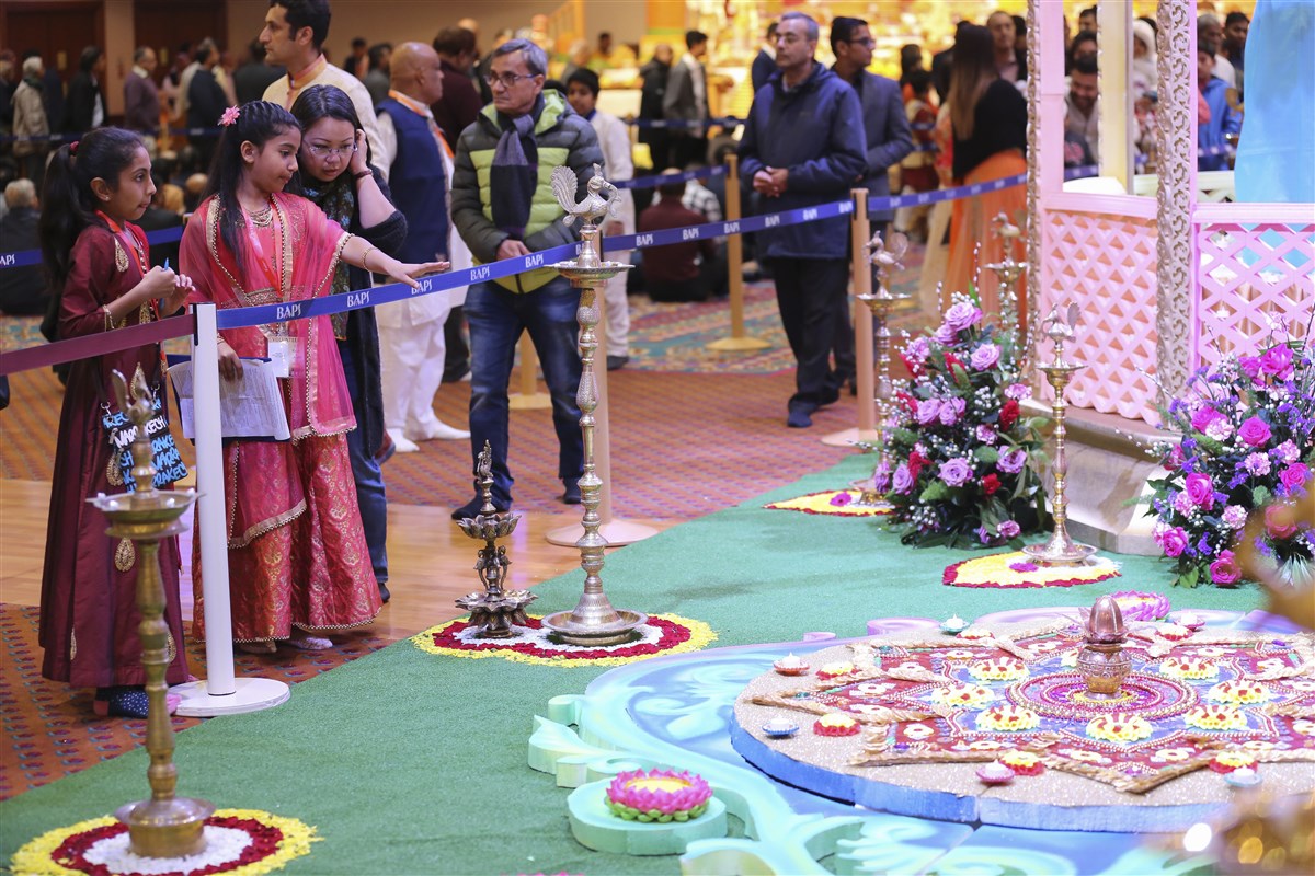 Young volunteers explain the deeper significance of the rangolis to a visitor