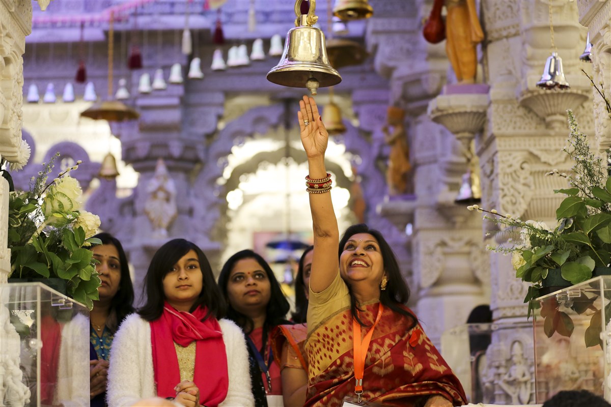 A visitor enjoys ringing the bell in the mandir