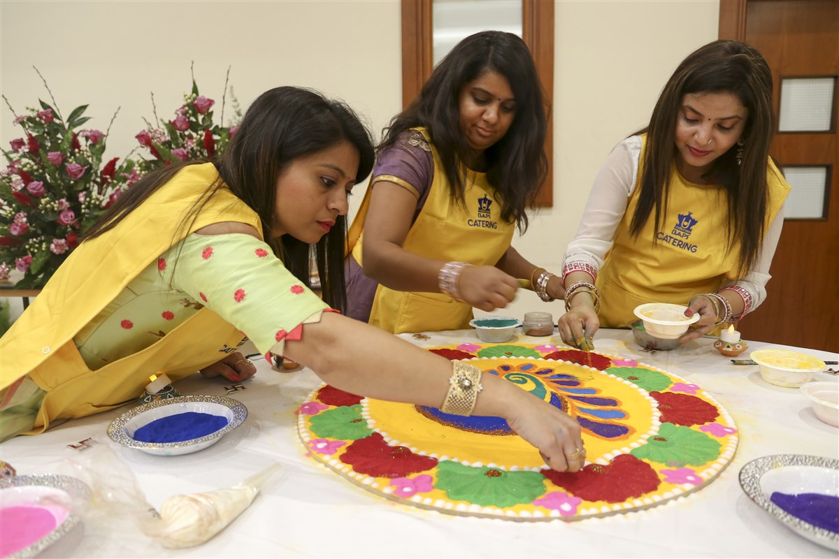 Volunteers prepare rangolis with fine powder paint