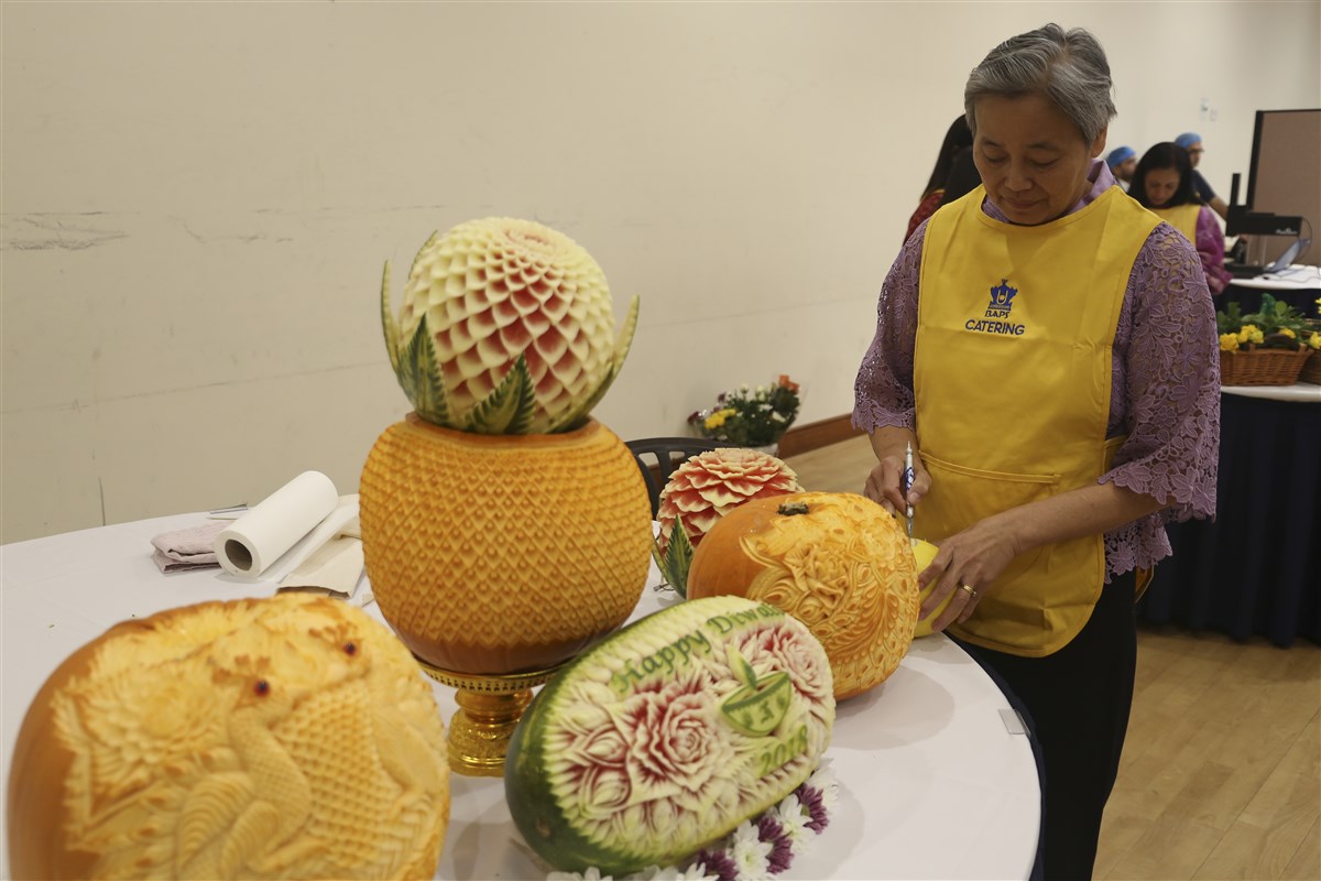 A volunteer prepares the intricately carved fruit sculptures