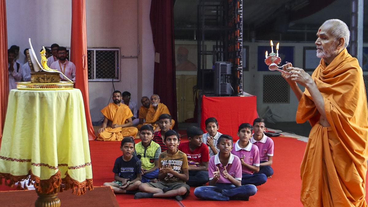 Swamishri performs arti in the evening symbolic Yogi Jayanti assembly