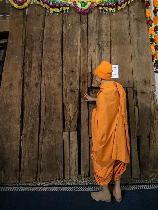 Swamishri engrossed in the darshan of a door sanctified by Bhagwan Swaminarayan