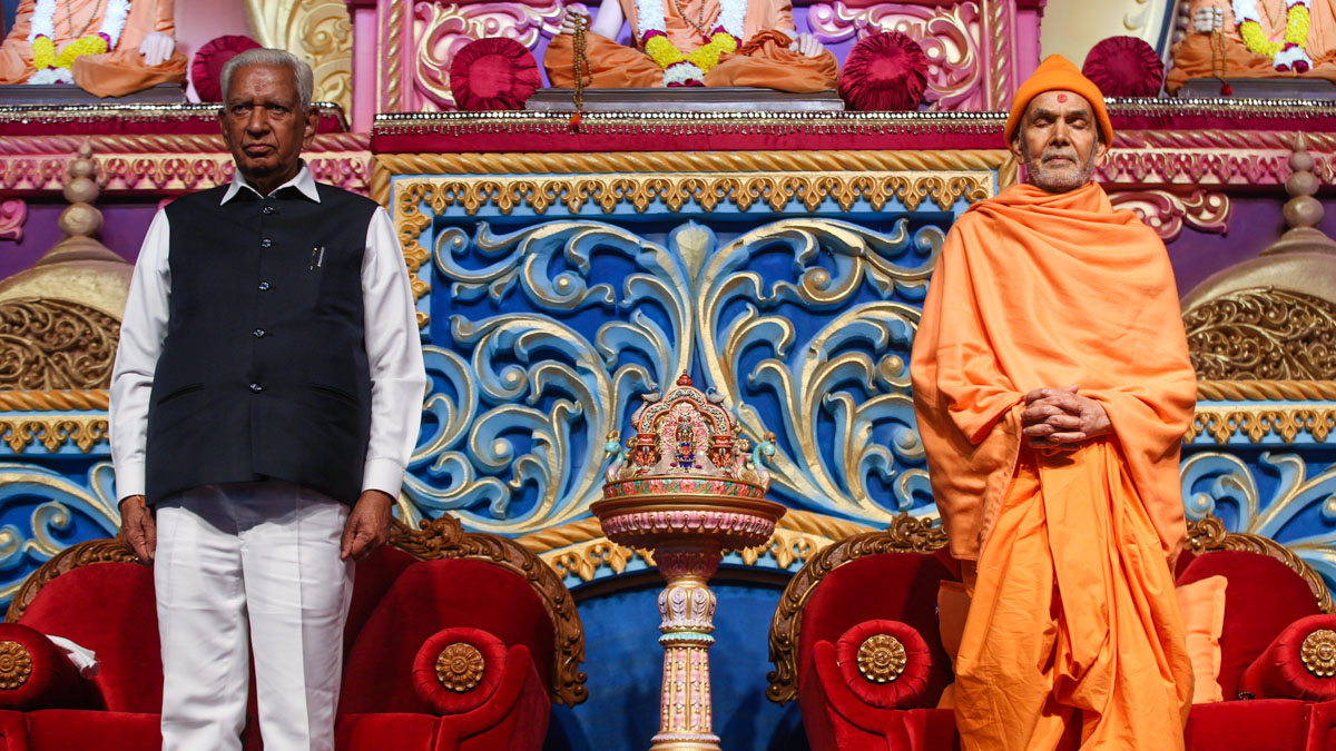 Swamishri and Shri Vajubhai Vala stand for the national anthem
