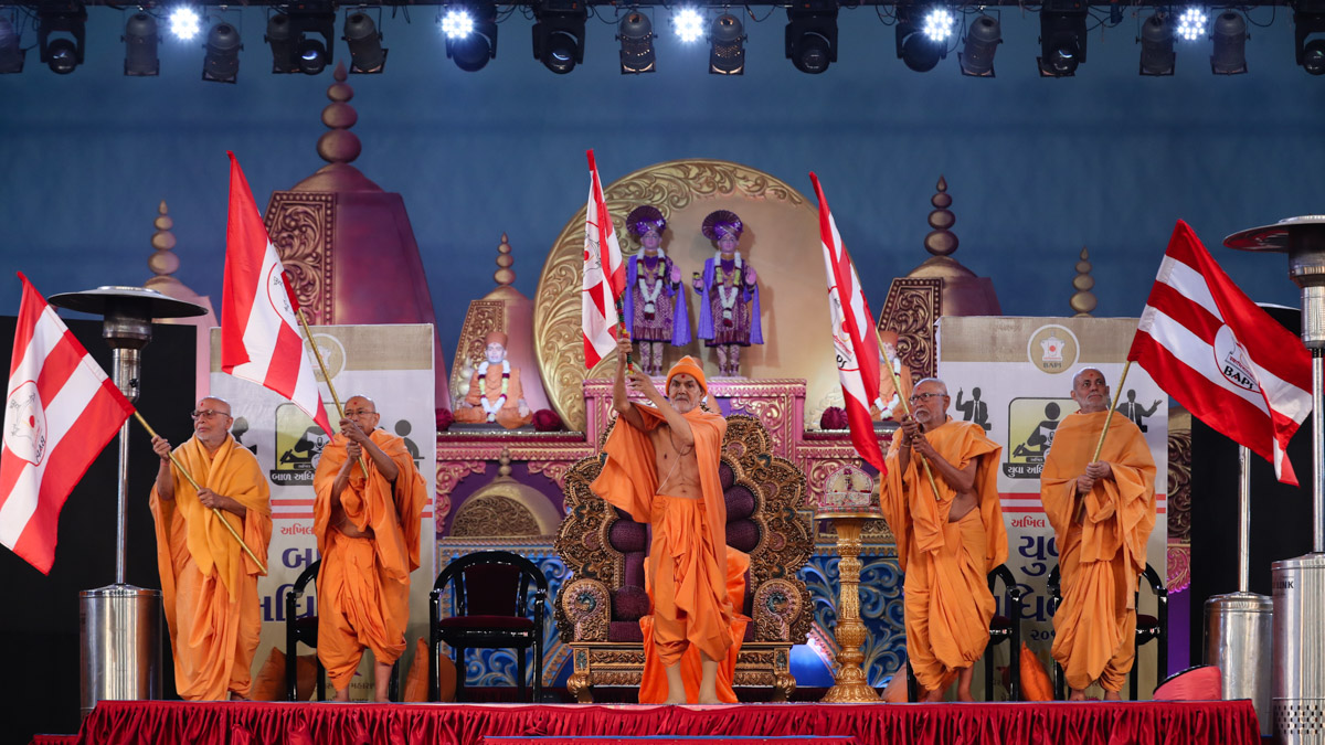 Swamishri and senior sadhus wave the BAPS flags