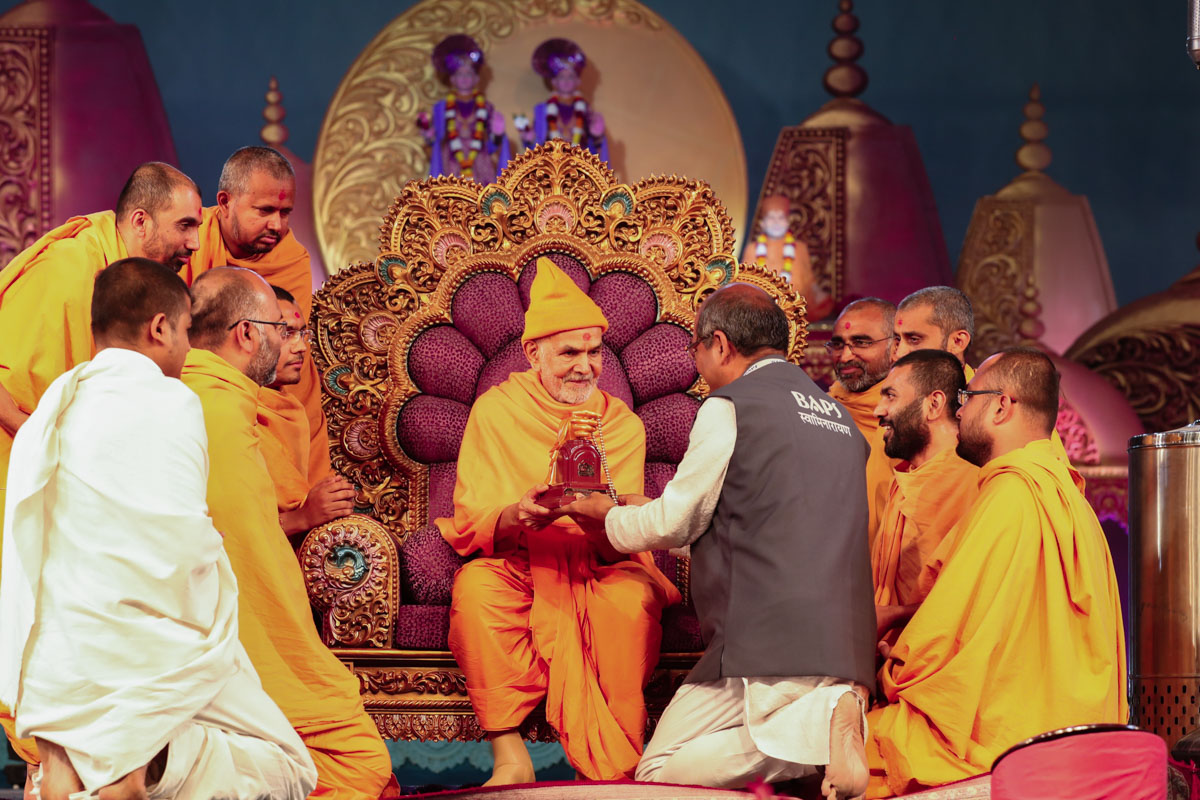 Swamishri presents a memento to a devotee