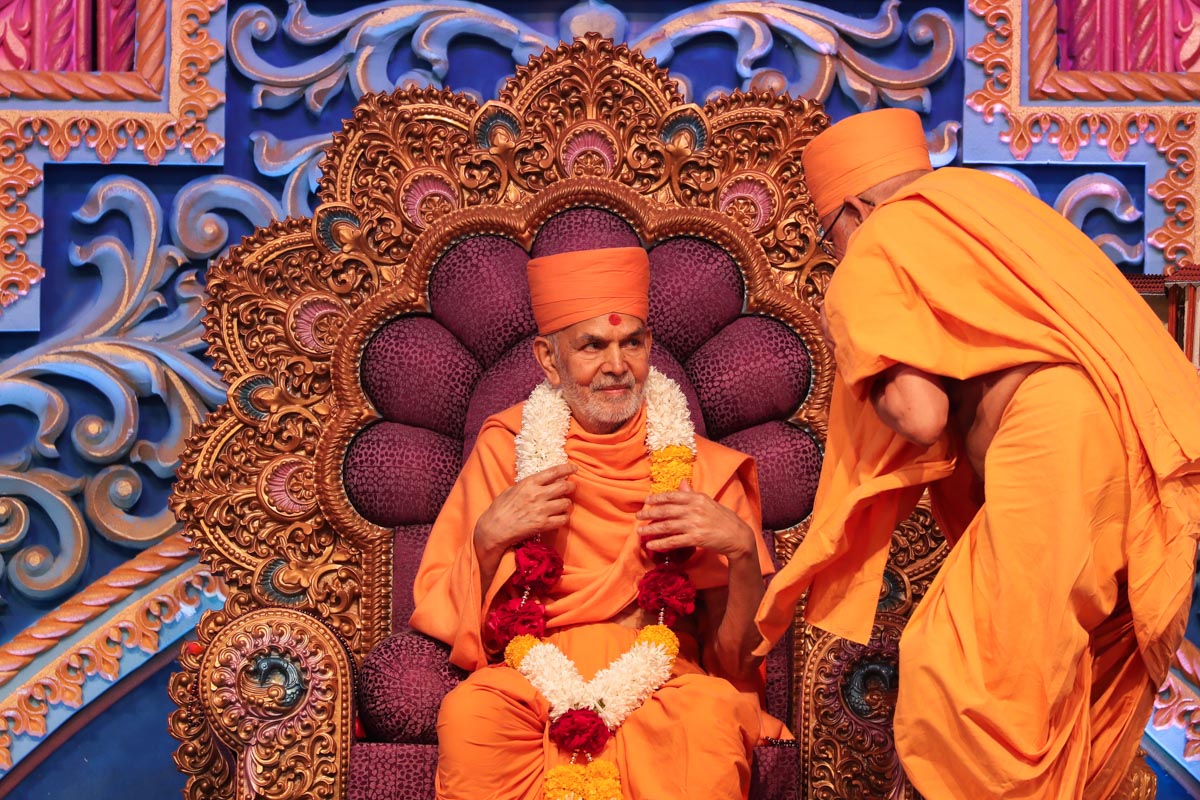 Pujya Bhaktipriya Swami (Kothari Swami) honors Swamishri with a garland