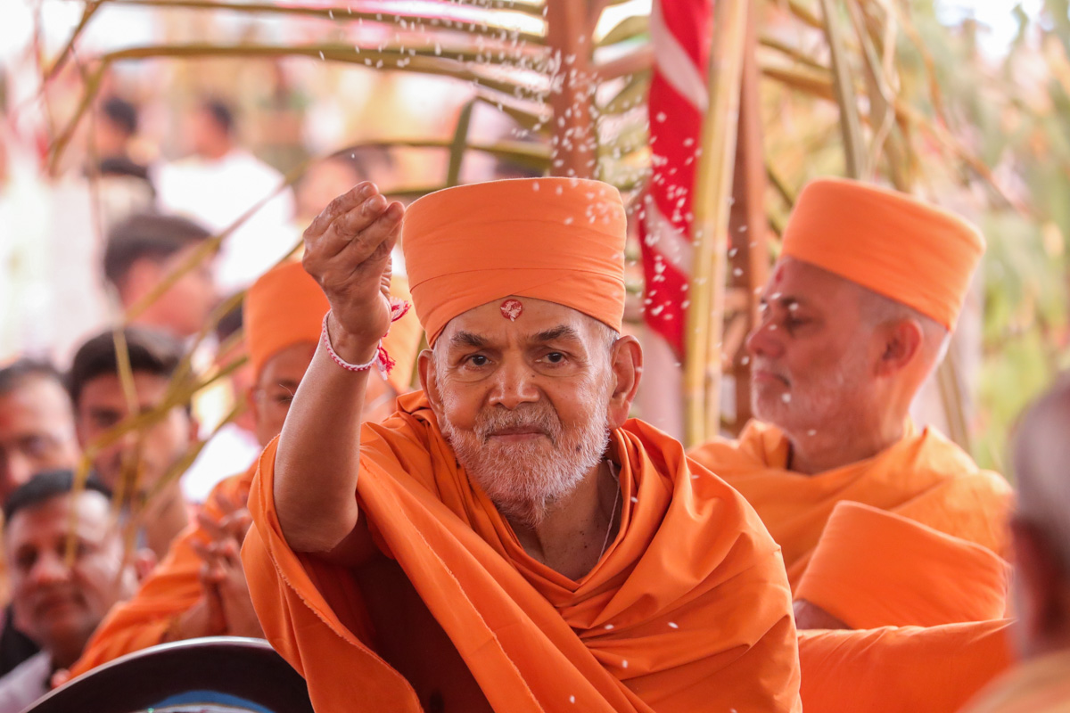Swamishri blesses devotees by showering rice grains