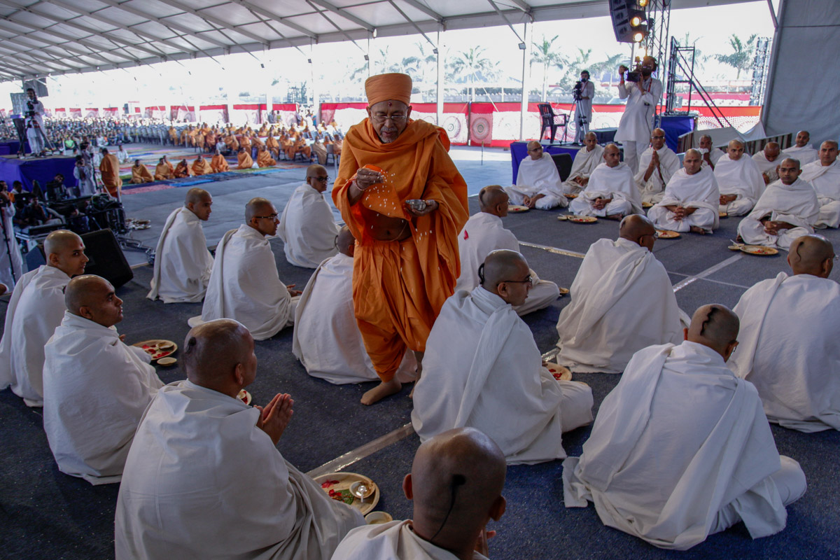 Pujya Tyagvallabh Swami blesses parshads by showering rice grains