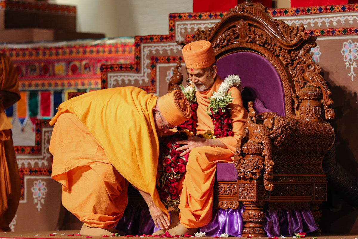Pujya Ghanshyamcharan Swami honors Swamishri with a garland