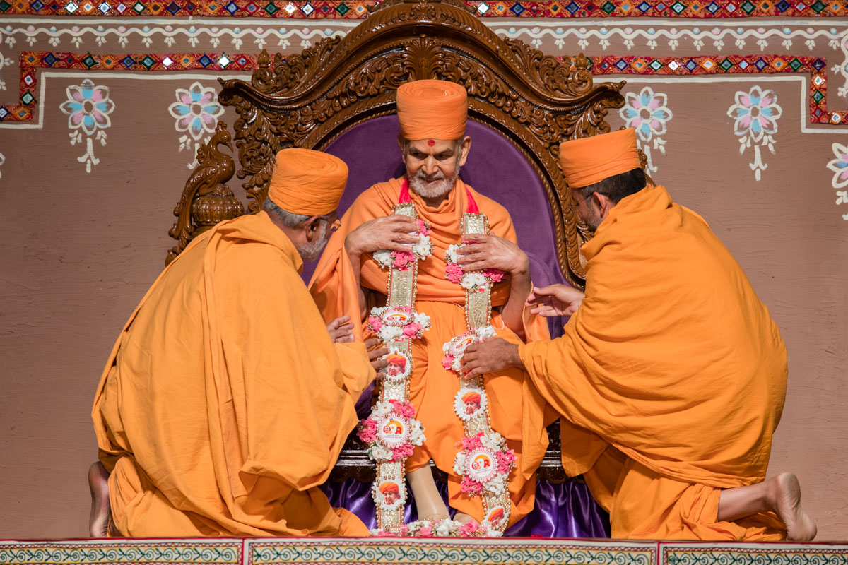 Brahmatirth Swami and Apurvamuni Swami honor Swamishri with a garland