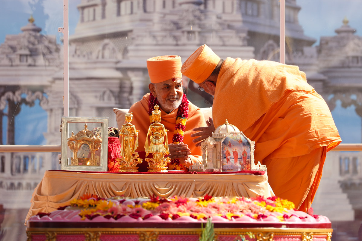 Pujya Ishwarcharan Swami honors Swamishri with a garland