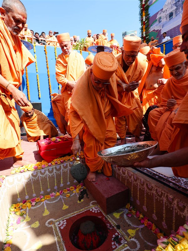 Pujya Ishwarcharan Swami pours cement in the foundation pit