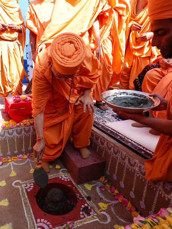Pujya Ghanshyamcharan Swami pours cement in the foundation pit