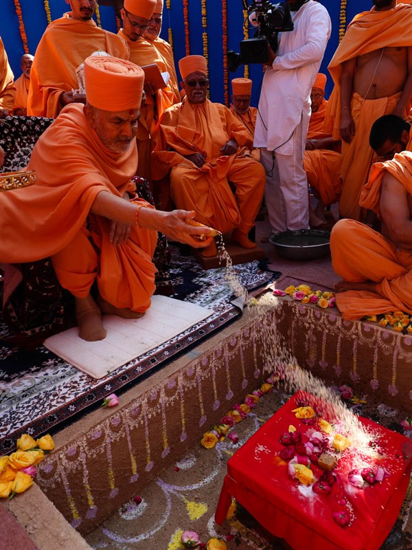 Swamishri shower rice grains on the main shila