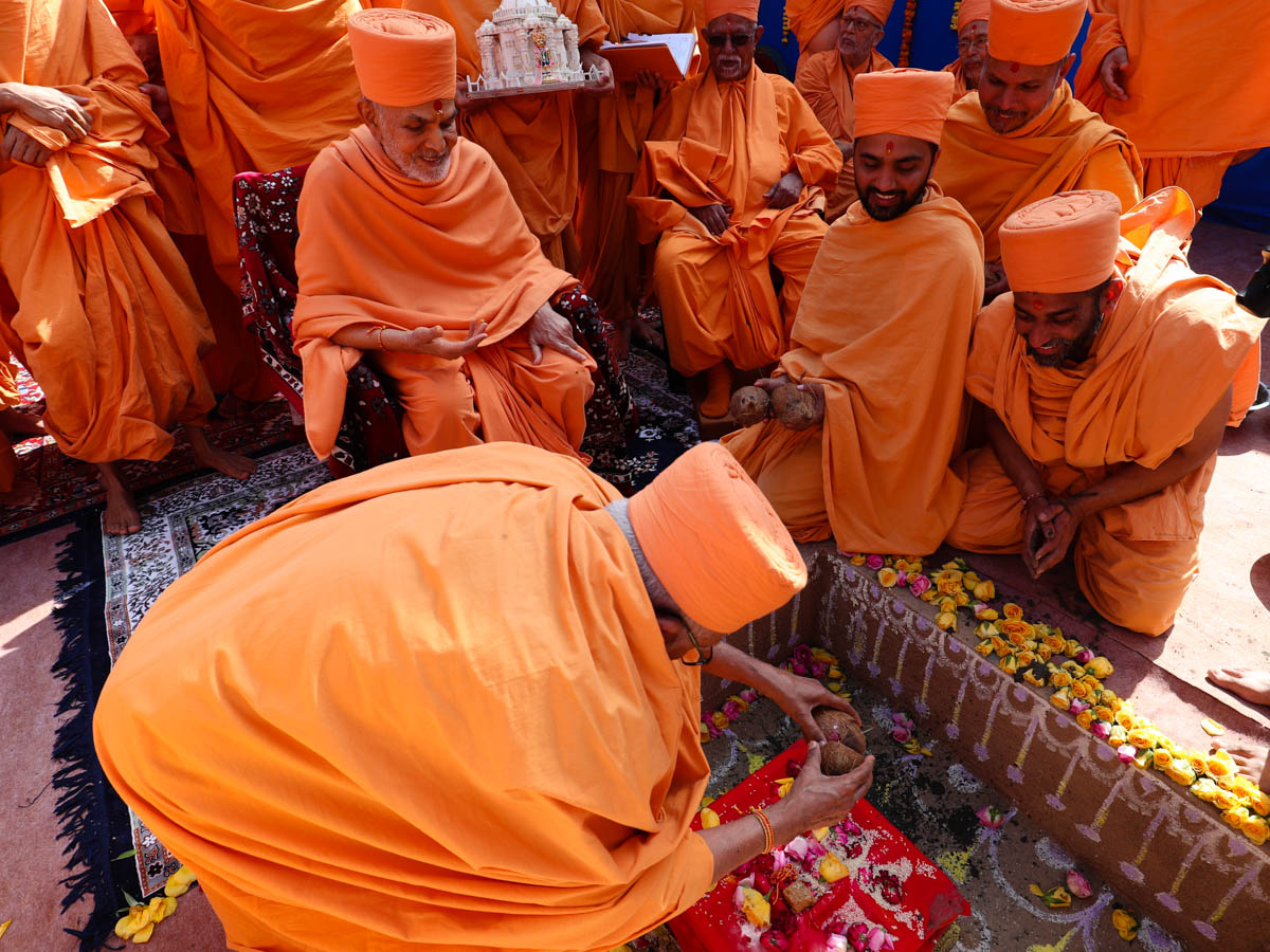 Pujya Kothari Swami ritually splits a coconut over the main shila