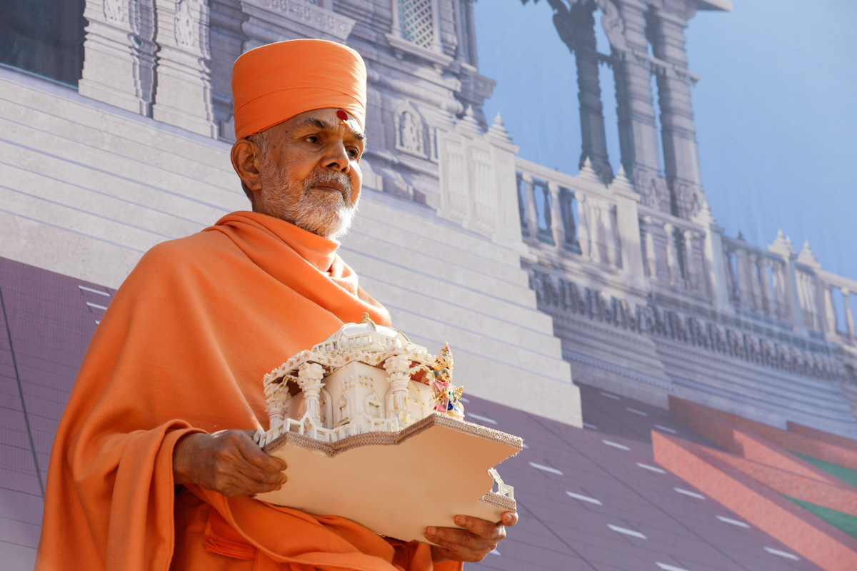 Swamishri standing with Shri Harikrishna Maharaj in front of a banner of Pramukh Swami Maharaj's Smruti Mandir