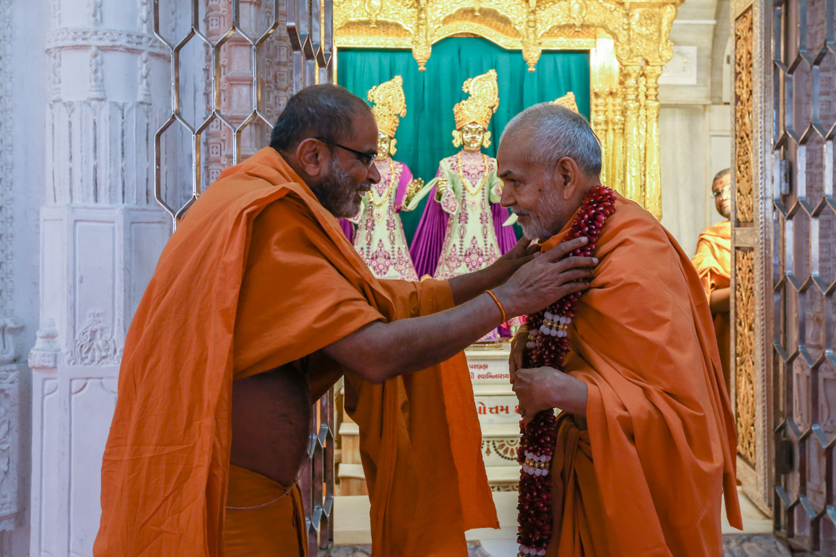 Gnaneshwar Swami honors Swamishri with a garland