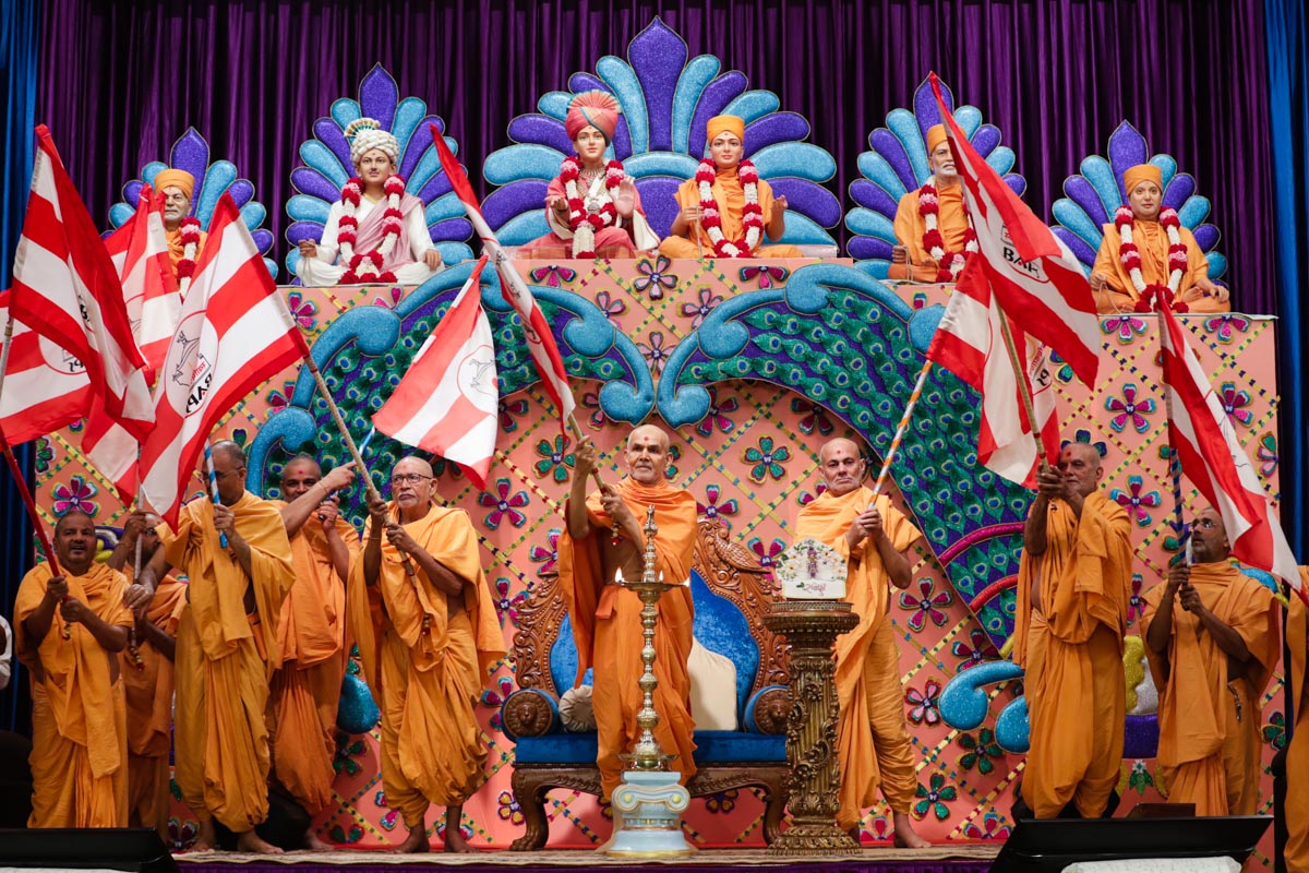Swamishri, Pujya Kothari Swami, Pujya Viveksagar Swami and sadhus wave BAPS flags