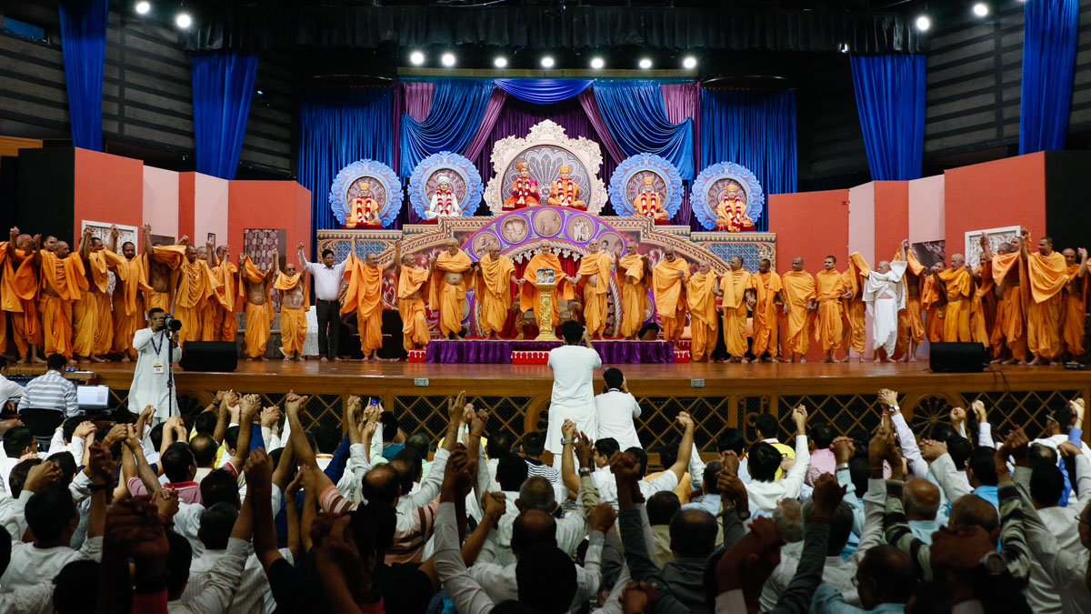 Swamishri joins hands with swamis and devotees in a gesture of unity