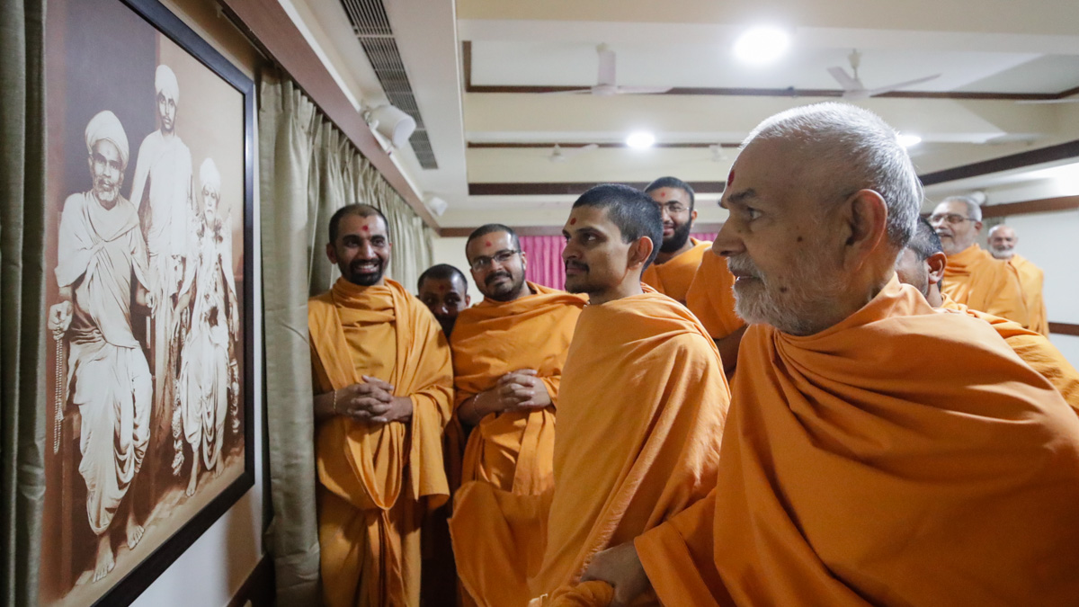 Swamishri observes a photo of Brahmaswarup Shastriji Maharaj, Brahmaswarup Yogiji Maharaj and Brahmaswarup Pramukh Swami Maharaj