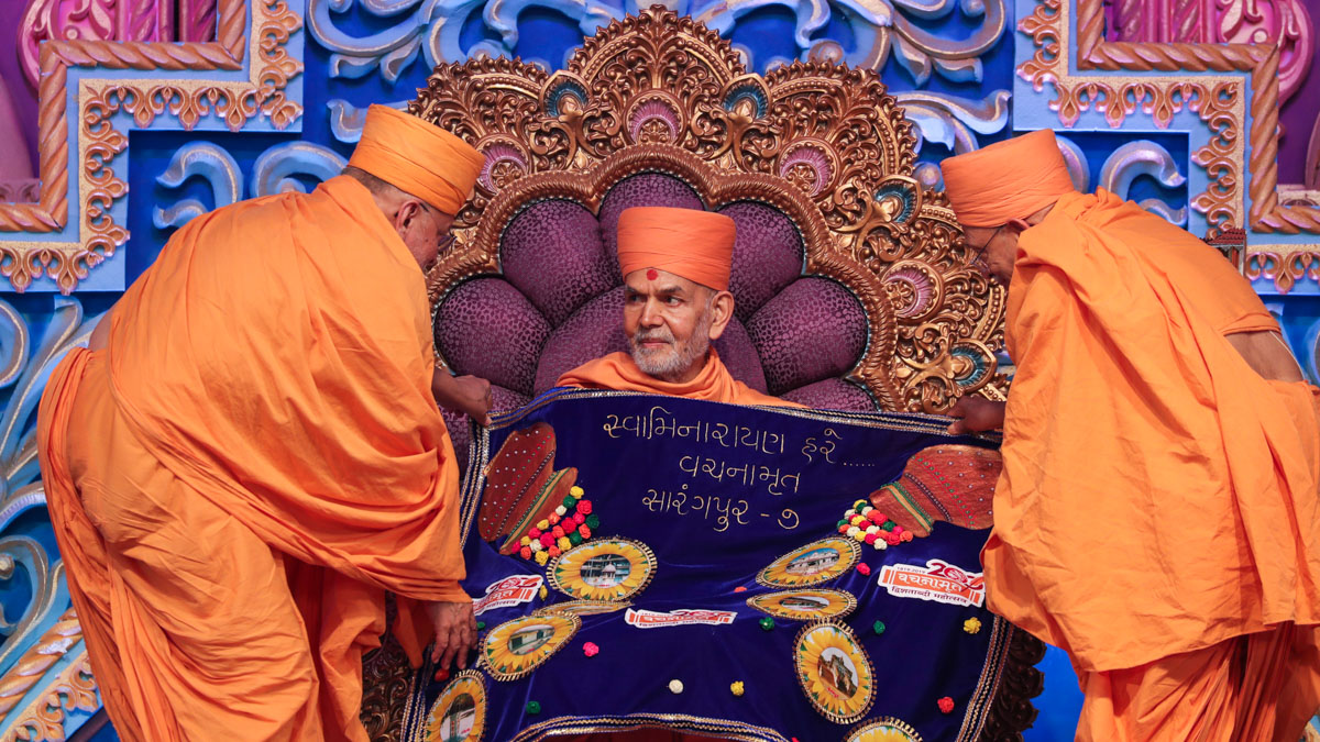 Pujya Ishwarcharan Swami and Pujya Tyagvallabh Swami honor Swamishri with a shawl