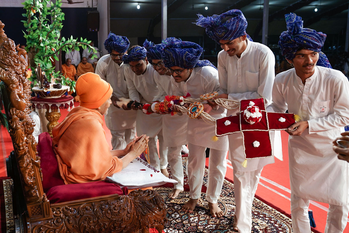 Karyakars present a garland to Swamishri