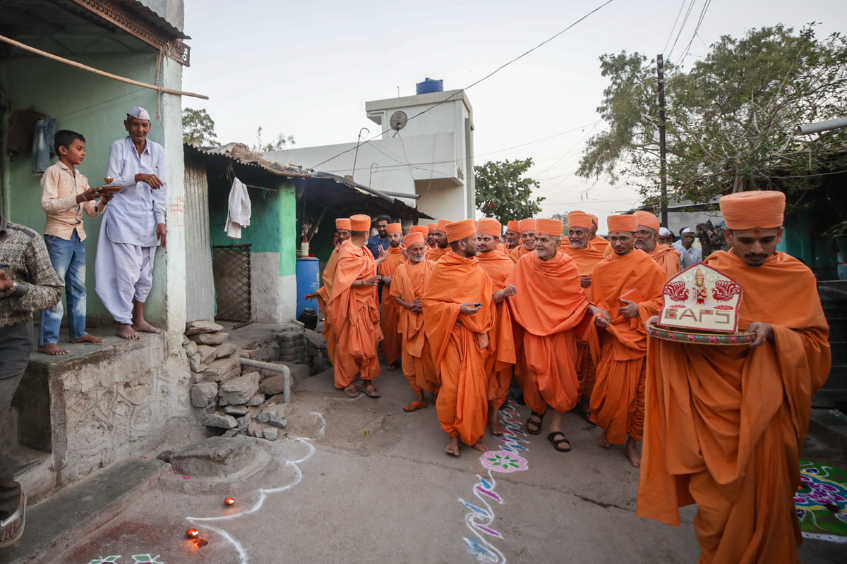 Devotees honor Swamishri as he walks through the streets of Mohadi