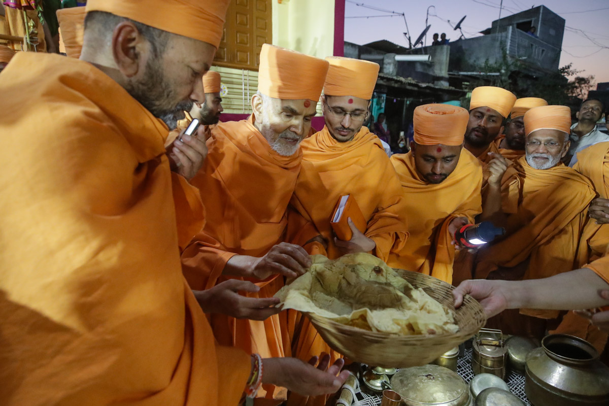 Swamishri inspects an example of the type of large, thin rotli made by Brahmaswarup Shastriji Maharaj