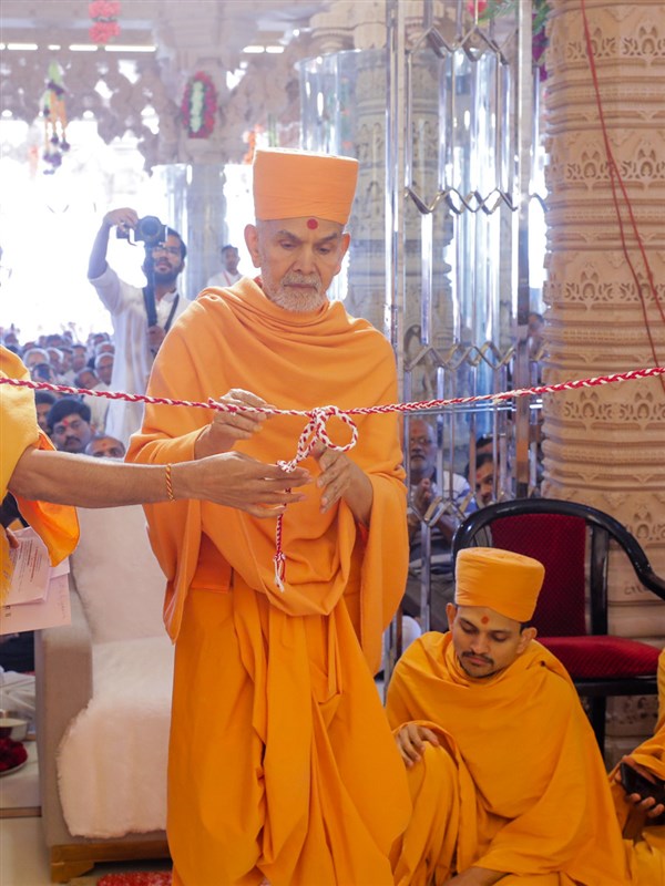 Swamishri unties the nadachhadi during the murti-pratishtha rituals
