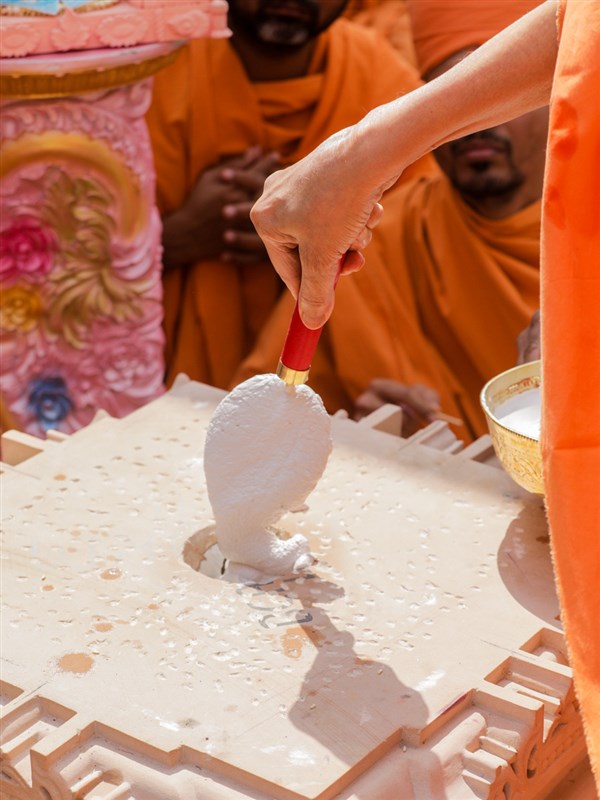 Swamishri fills the pillar with a special adhesive mixture