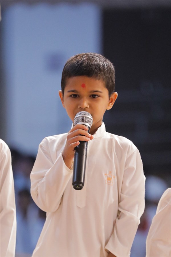 A child presents mukhpath during Swamishri's puja