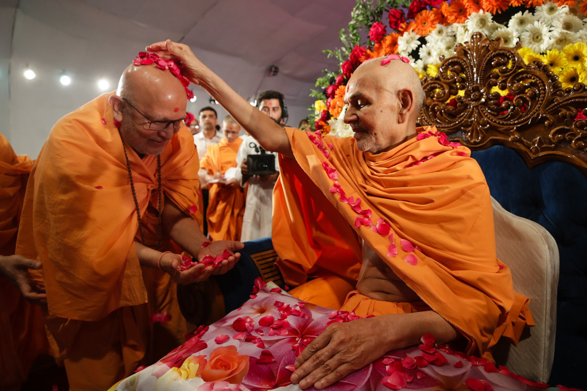 Swamishri showers flower petals on Pujya Ghanshyamcharan Swami