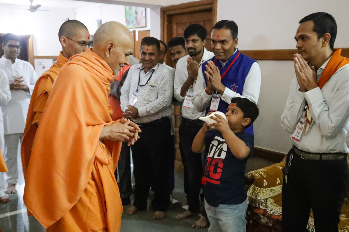 A child blows a conch before Param Pujya Mahant Swami Maharaj