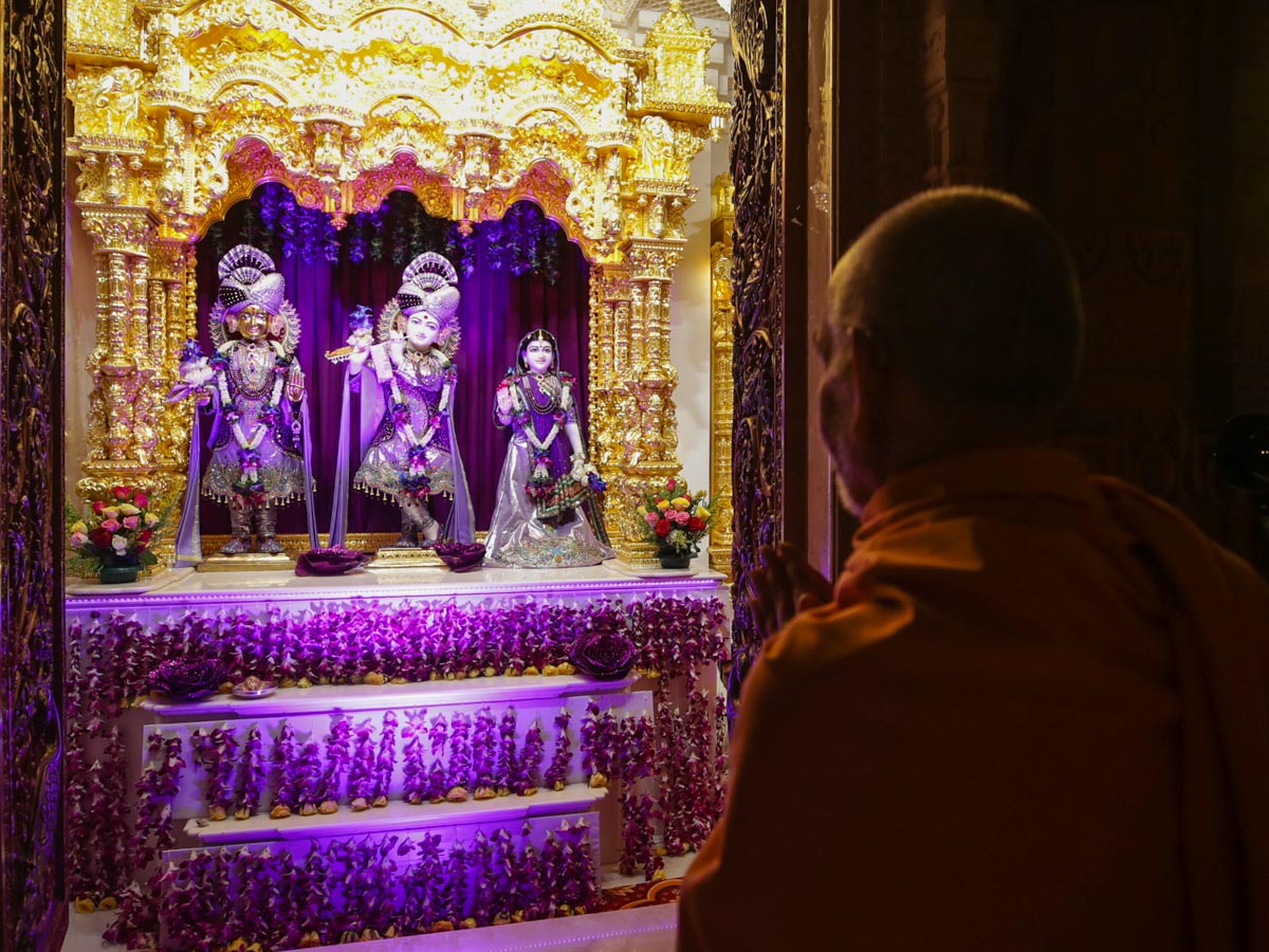 Swamishri engrossed in the darshan of Shri Harikrishna Maharaj and Shri Radha-Krishna Dev