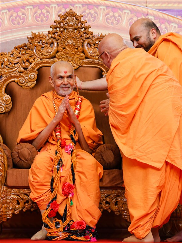 Pujya Ghanshyamcharan Swami honors Swamishri with a garland of malas
