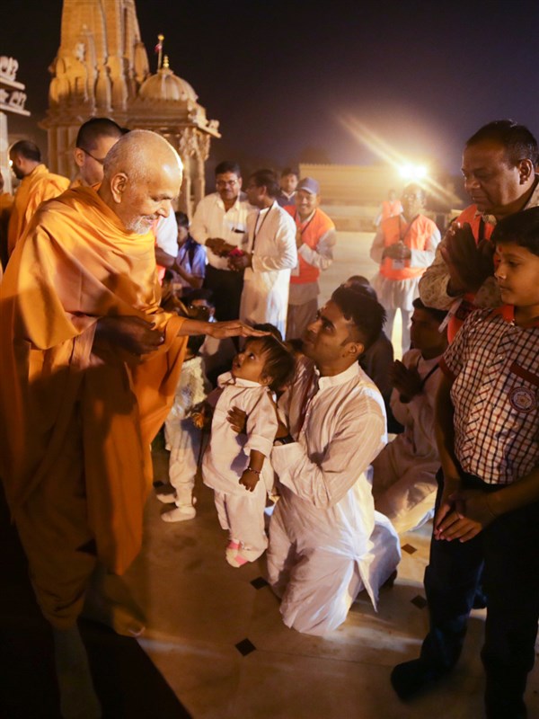 Swamishri blesses a child in the mandir pradakshina