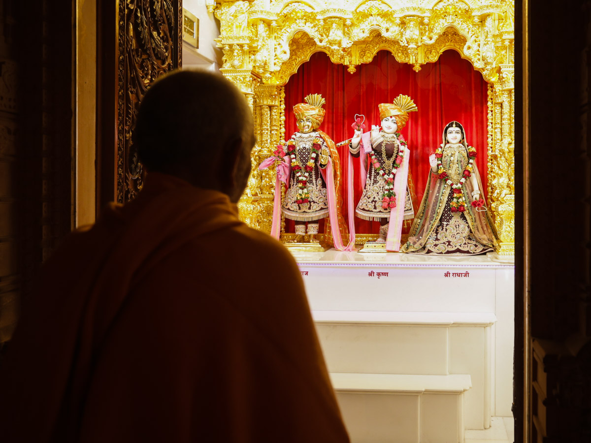 Param Pujya Mahant Swami Maharaj engrossed in the darshan of Shri Harikrishna Maharaj and Shri Radha-Krishna Dev